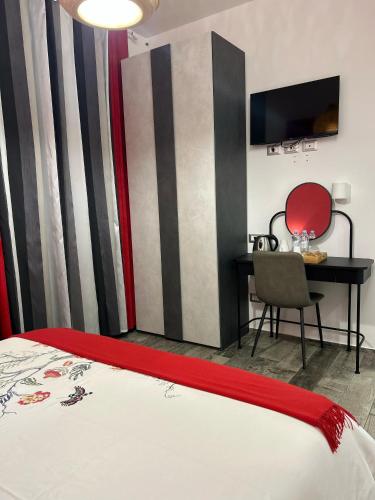 a bedroom with a bed and a desk and a television at Rosso Relativo in Acilia