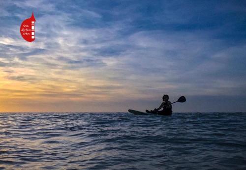 a person sitting on a kayak in the ocean with a kite at Villa clair de Falaises in Le Tréport
