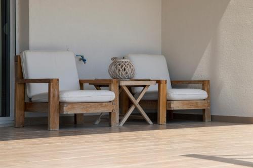 two chairs and a table with a vase on it at Oceana - Exclusive Beachfront Villa with Private Pool and BBQ by GG in Alexandroupoli