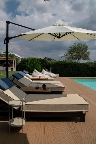 a group of lounge chairs and an umbrella next to a pool at Oceana - Exclusive Beachfront Villa with Private Pool and BBQ by GG in Alexandroupoli