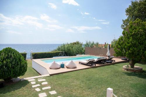 a swimming pool with two white pillows next to the ocean at Oceana - Exclusive Beachfront Villa with Private Pool and BBQ by GG in Alexandroupoli