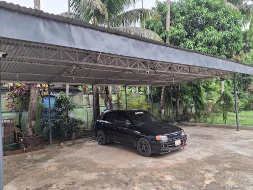 a black car parked under a metal garage at Green Park Tea Resort Sreemangal in Sreemangal