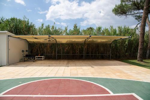 a pavilion with a bench under awning on a basketball court at Oceana - Exclusive Beachfront Villa with Private Pool and BBQ by GG in Alexandroupoli