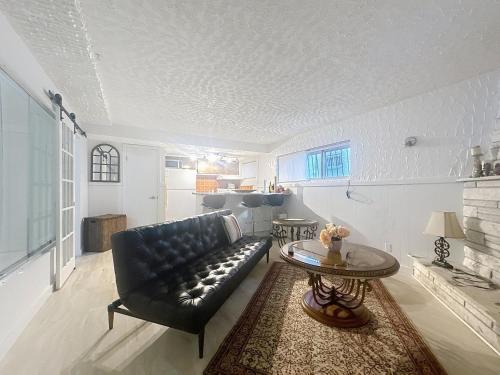 モントリオールにあるLogement 1 pièce Cozy - Parfait pour Courts Séjoursのリビングルーム(黒い革張りのソファ、テーブル付)
