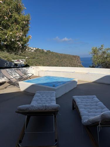 a room with a table and two chairs and a pool at Villa Vista Mare a Filicudi in Filicudi