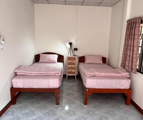 Dos camas en una habitación con sábanas rosas. en BB Sweet Home, en Ban Hin Kong (1)
