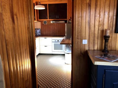 - une cuisine avec des murs en bois et des appareils blancs dans l'établissement Chalet Les Pommiers, à Vallouise