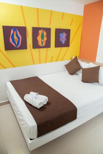 a bedroom with a white bed with orange and yellow walls at Bajo la luna hotel in Medellín