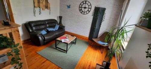 a living room with a leather couch and a table at Gite au Petit Verger in Masevaux