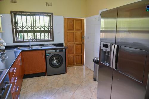 a kitchen with a refrigerator and a washing machine at Leopard Tree Apartments in Lusaka