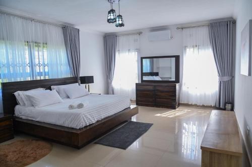 a bedroom with a large bed and a mirror at Leopard Tree Apartments in Lusaka