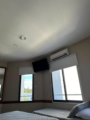 a bedroom with two windows and a bed and a fan at Hotel Vicente López in Vicente López