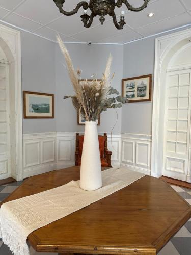 a white vase with flowers in a room at Hotel Vicente López in Vicente López