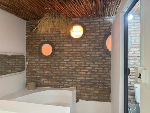a bathroom with a brick wall with two windows at Vicnie House Cần Thơ in Bình Thủy