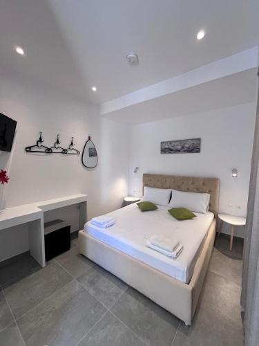 a white bedroom with a bed and a desk at Villa Agur Kapo in Ksamil