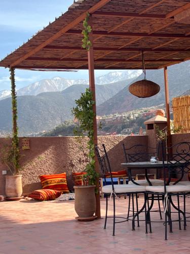 a patio with a table and chairs with mountains in the background at Tazart Lodge in Marrakech