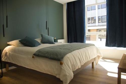 une chambre avec un lit et une grande fenêtre dans l'établissement Suite Izambard 4 pers Standing en centre ville, à Charleville-Mézières