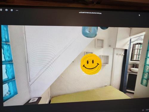 un sourire jaune sur le mur d'une pièce dans l'établissement maison atypique terrasse vue st victoire, à La Celle-sous-Gouzon