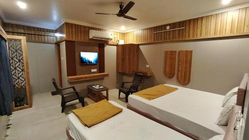 a room with two beds and a tv in it at Hotel Govindh Heights in Tirupati