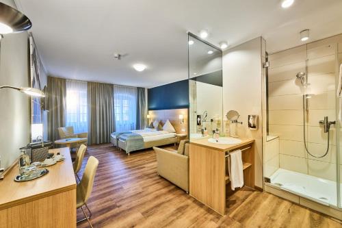 a hotel room with a bed and a bathroom at Hotel & Gasthaus DAS RÖHRL Straubing in Straubing