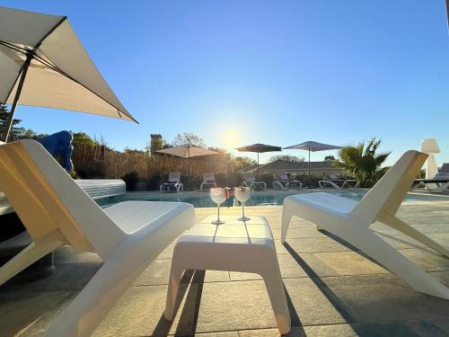 two white chairs and a table with wine glasses at chambre villa 4 in Servas