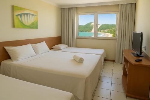 a hotel room with two beds and a television at Ponta Negra Flats Partic in Natal