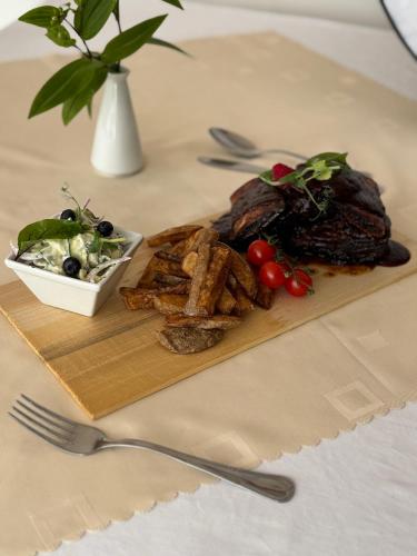 a wooden cutting board with a plate of meat and a salad at Kosewo 78 Family Hotel & Spa in Kosewo