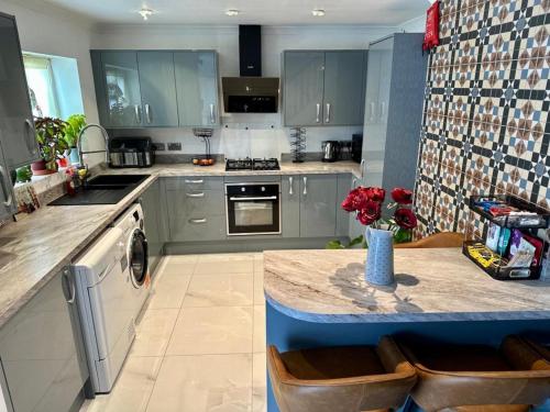 a kitchen with gray cabinets and a table with flowers on it at 4 bed masonette with Garden in London