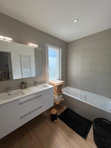 une salle de bain avec deux lavabos, une baignoire et un miroir dans l'établissement Ker Phan Cozy urban cottage with hot tub, à Saint-Aubin-du-Cormier