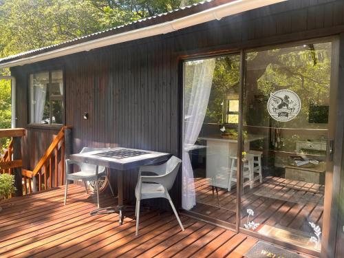 eine Terrasse mit Tisch und Stühlen auf einem Deck in der Unterkunft Griffin's Nest Cottage in Mbabane