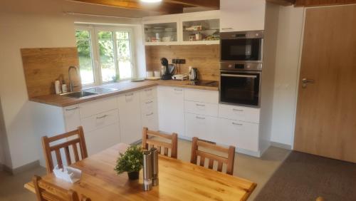 a kitchen with white cabinets and a wooden table at Penzion V Kopci in Kořenov