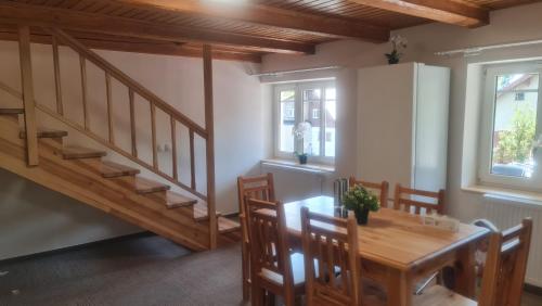 a dining room with a wooden table and stairs at Penzion V Kopci in Kořenov