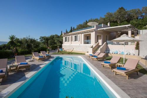 a swimming pool with lounge chairs and a house at Villa Pelekas in Mesochórion