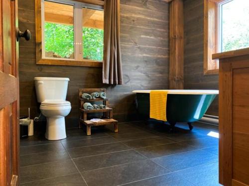 a bathroom with a toilet and a bath tub at Superbe maison à 1 kilomètre de la Marina in LʼAnse-Saint-Jean