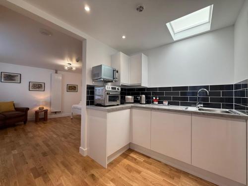 a kitchen with white cabinets and a living room at Gresham in Kent