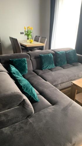 a couch with green pillows sitting in a living room at Bulwar Apartament Stare Miasto in Głogów