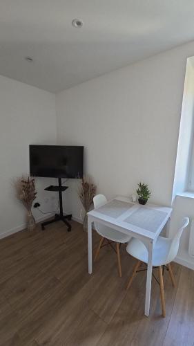 une salle à manger blanche avec une table et une télévision dans l'établissement Joli Studio plein centre ville, à Morteau