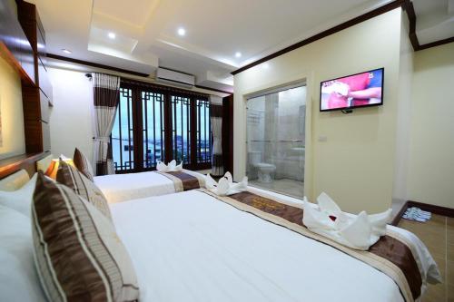 a bedroom with two beds and a tv on a wall at Vientiane Luxury Hotel in Vientiane
