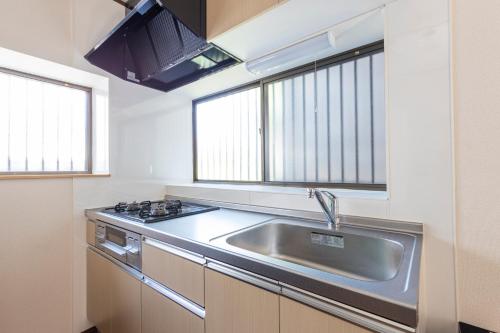 a kitchen with a stainless steel sink and two windows at Sakura in Tokyo