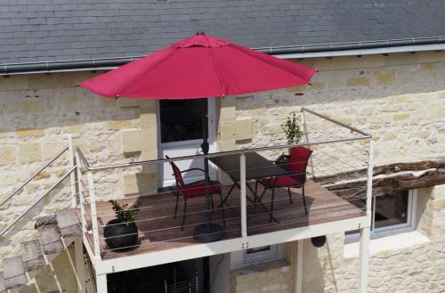 a table and chairs on a balcony with a red umbrella at Le gîte 24 proche du Futuroscope - Jacuzzi compris in Beaumont