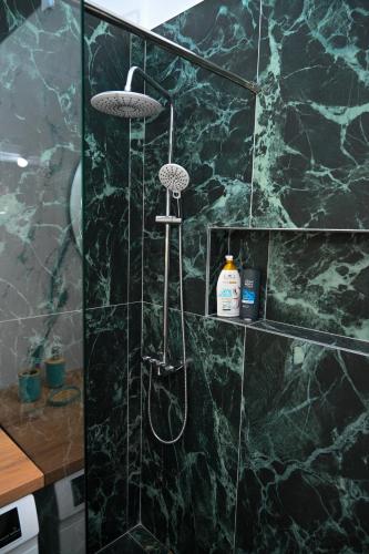 a bathroom with a shower with a black marble wall at Maison de jolie in Golem