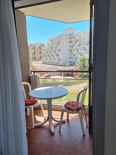 une table et des chaises sur un balcon avec vue sur un immeuble dans l'établissement Front de mer, Wifi, joli appartement 4 couchages, secteur Lydia Grande plage, au Barcarès