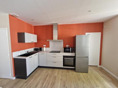 - une cuisine avec des placards blancs et un mur orange dans l'établissement Appartement Le 94, à Lurcy-Lévis