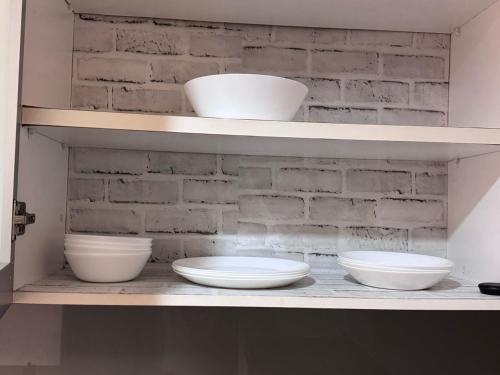 a shelf with three bowls on it with a brick wall at Relaxhome In Bukit Bintang in Kuala Lumpur