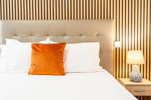 a bed with white pillows and an orange pillow at Holiday Home Funchal Center in Funchal