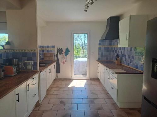 a large kitchen with white cabinets and blue tiles at Magnifique Villa avec piscine in Cadenet