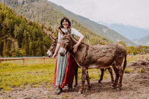 a woman is standing next to a donkey at Hotel Bergschlössl in Luson