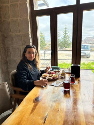 a woman sitting at a table with a plate of food at Gala Cave Cappadocia in Goreme