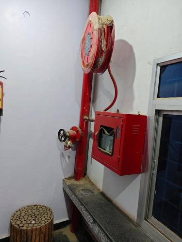 a red fire hydrant sitting on the side of a wall at Raj Hotel - Since 1960 in Sultānpur