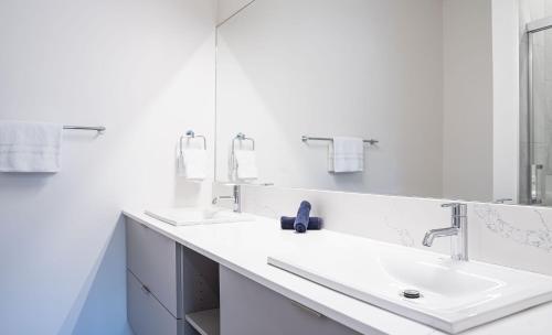 a white bathroom with two sinks and a mirror at Mountainside Revival by Revelstoke Vacations in Revelstoke